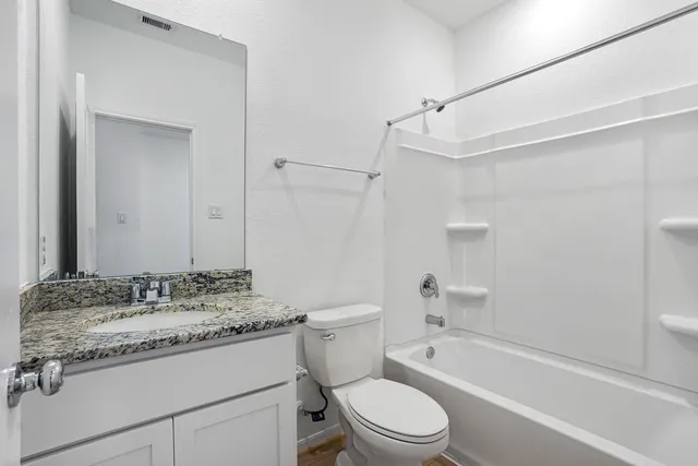 a bathroom with a granite countertop sink a toilet and shower
