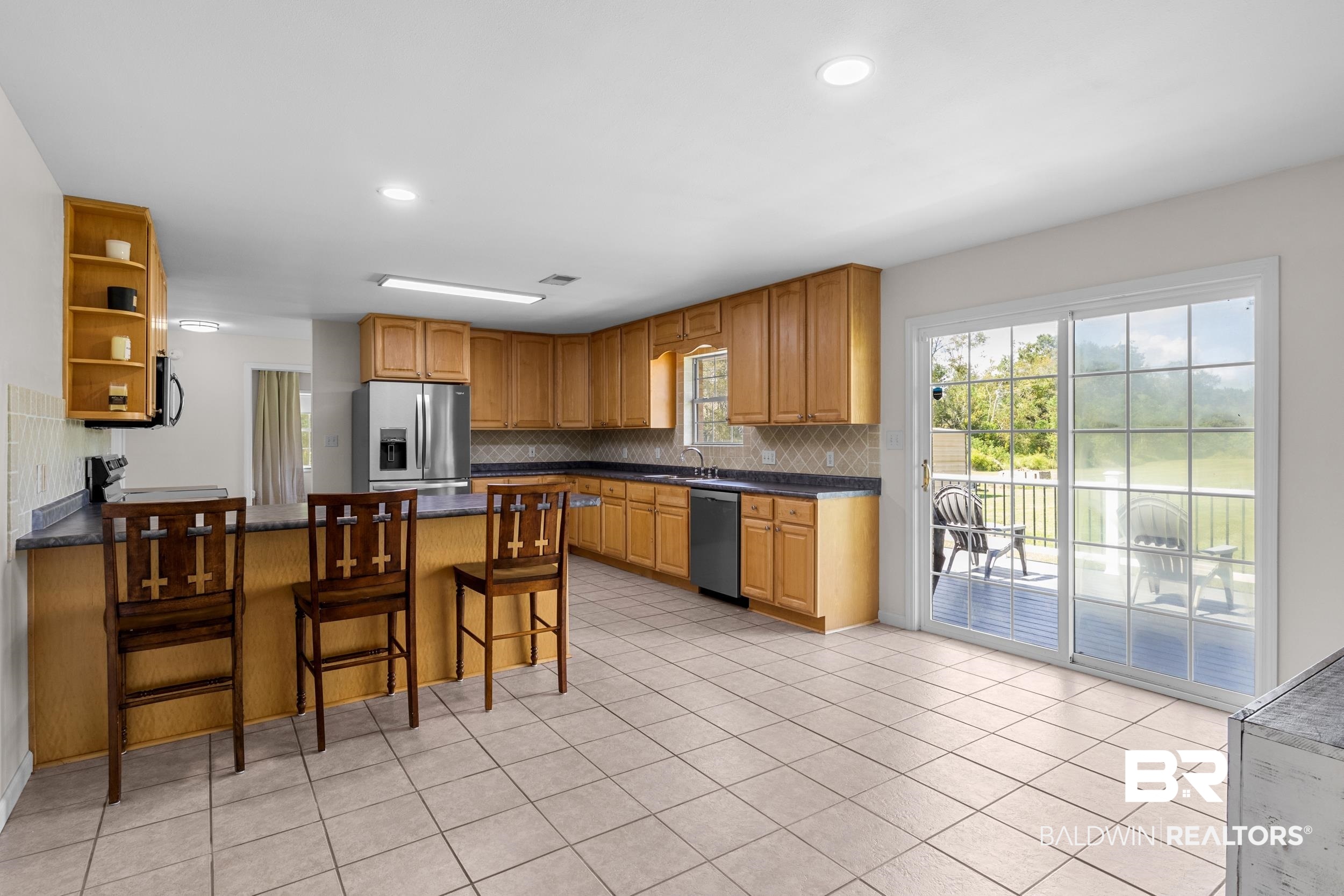 17689 Brewer Road Foley, AL 36535 - Photo 24 of 54 Kitchen with appliances with stainless steel finishes, decorative backsplash, light tile patterned floors, a kitchen bar, and sink