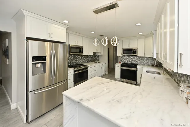 a kitchen with stainless steel appliances kitchen island a stove a refrigerator a oven and a sink with large countertops