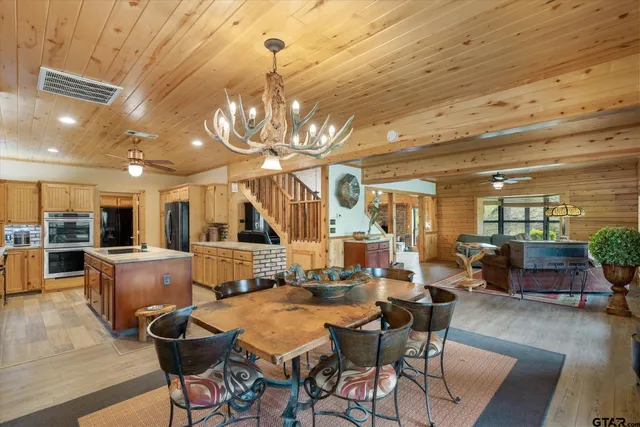 a dining room with wooden floor a chandelier a wooden table and chairs