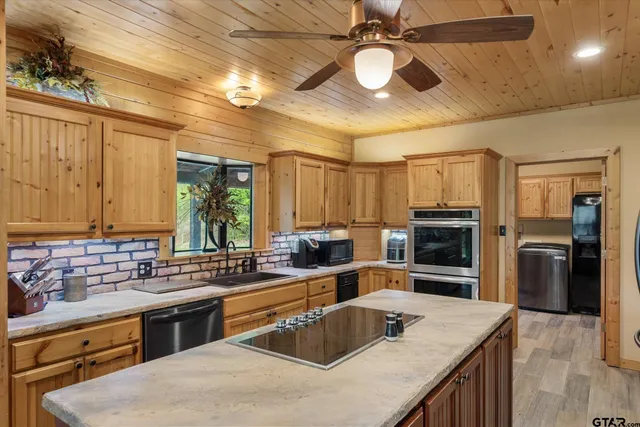 a kitchen with stainless steel appliances granite countertop a sink a stove cabinets counter space and a window