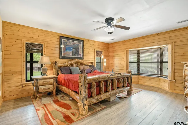 a spacious bedroom with a bed and a large window with wooden floor