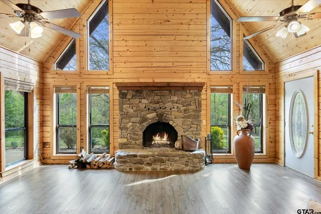 a view of an empty room with wooden floor fireplace and a window