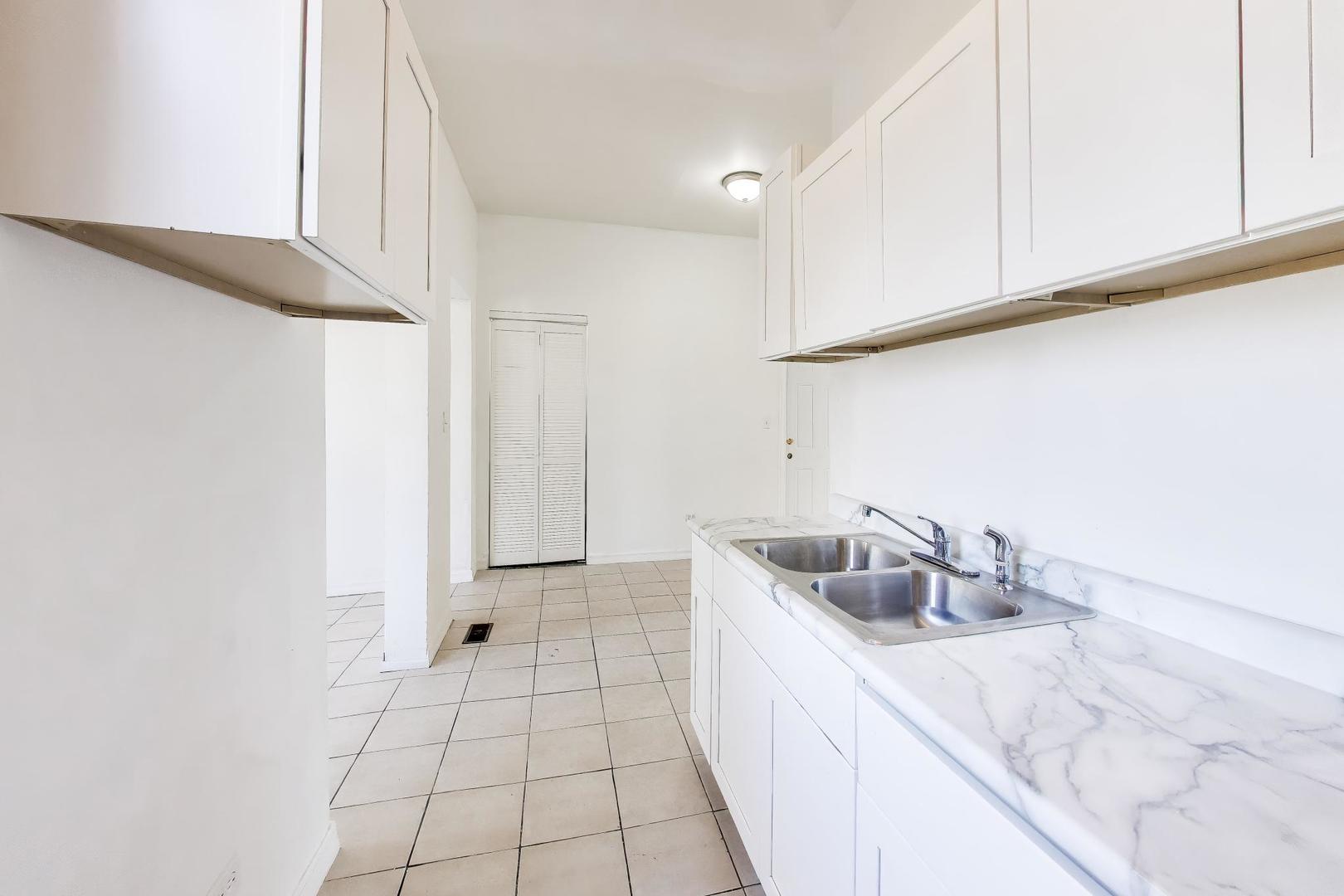 6853 South Perry Avenue Chicago, IL 60621 - Photo 8 of 28 a kitchen with granite countertop a sink a stove and cabinets