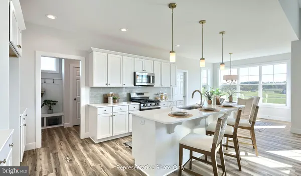 a kitchen with stainless steel appliances kitchen island granite countertop a table chairs and a wooden floor