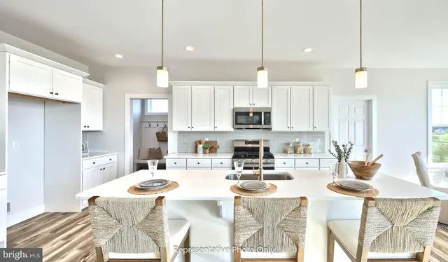 a kitchen with stainless steel appliances kitchen island granite countertop a stove a sink a refrigerator a dining table and chairs with wooden floor
