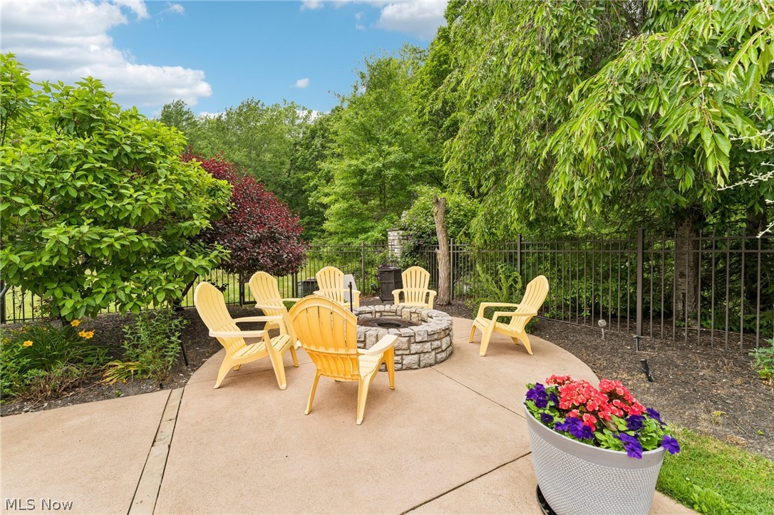 8874 Sharp Road Olmsted Falls, OH 44138 - Photo 24 of 42 Curved concrete patio featuring a stone-clad fire pit, surrounded by a wrought-iron fence