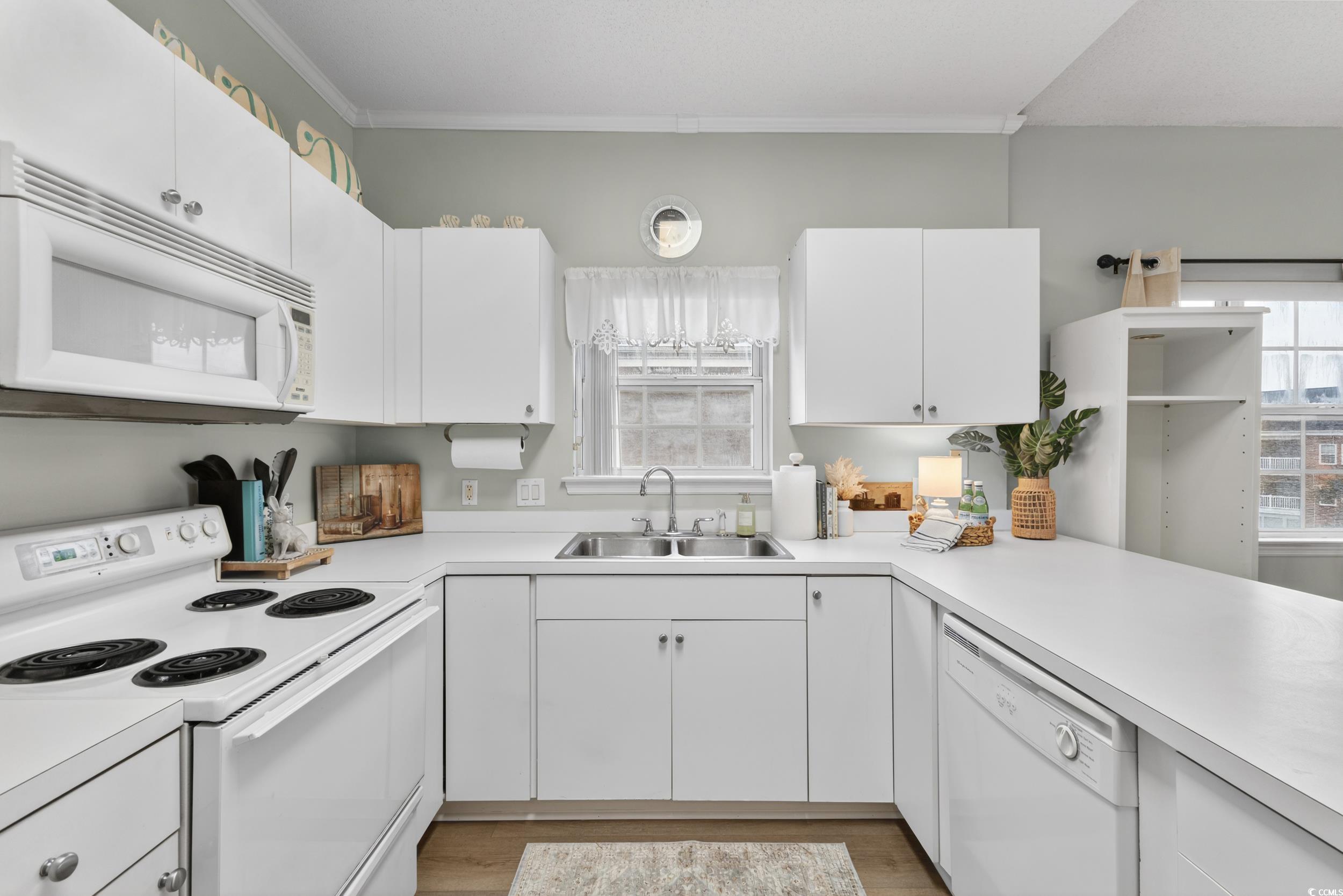 3915 Gladiola Court, Unit 301 Myrtle Beach, SC 29588 - Photo 5 of 24 Kitchen featuring white appliances, white cabinetry, light countertops, light wood-style floors, and crown molding