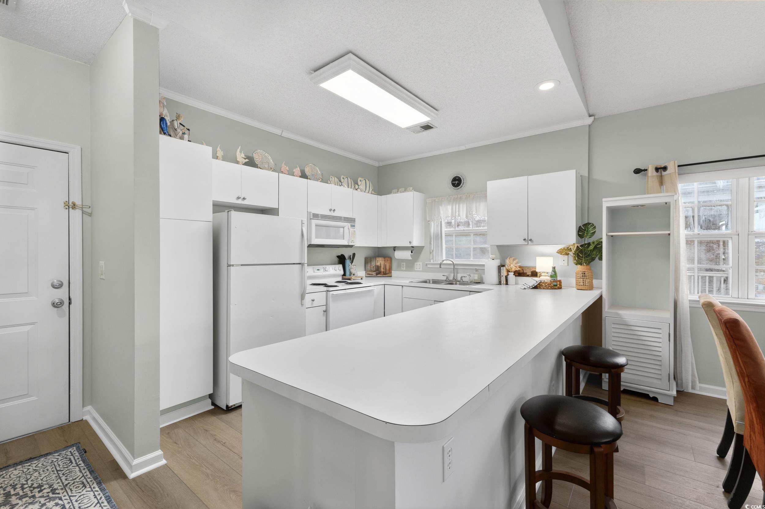 3915 Gladiola Court, Unit 301 Myrtle Beach, SC 29588 - Photo 6 of 24 Kitchen with light countertops, white appliances, a peninsula, white cabinets, and light wood finished floors