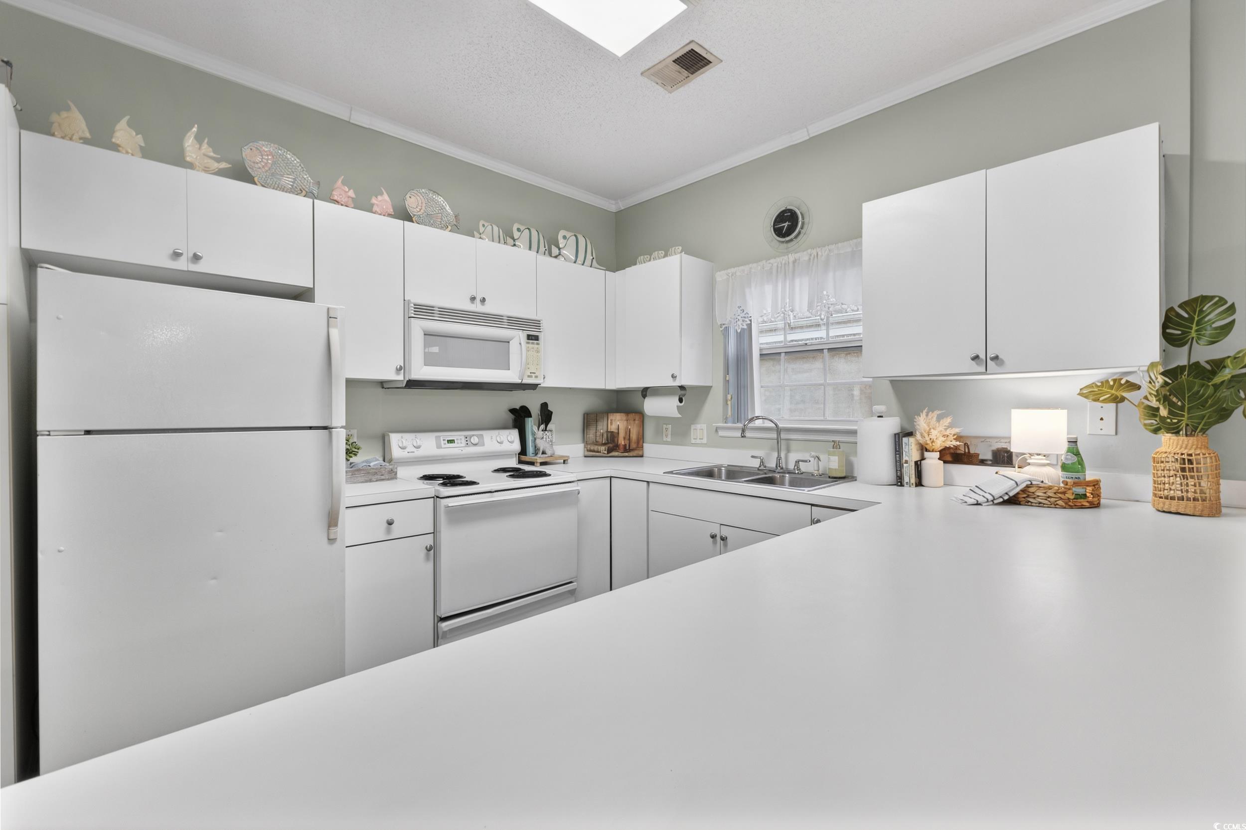 3915 Gladiola Court, Unit 301 Myrtle Beach, SC 29588 - Photo 8 of 24 Kitchen with white appliances, light countertops, ornamental molding, white cabinetry, and a textured ceiling