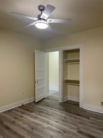 an empty room with wooden floor closet and windows