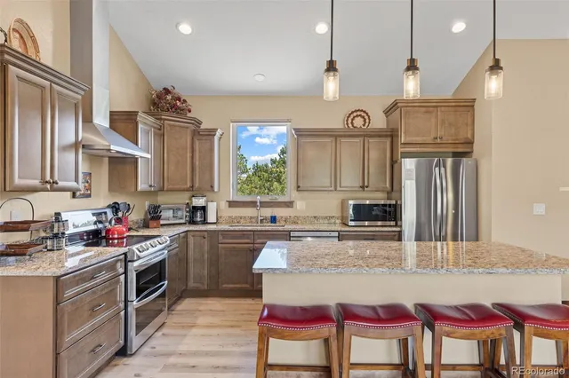 a kitchen with kitchen island granite countertop a stove a sink and a refrigerator