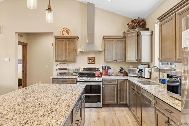 a kitchen with stainless steel appliances granite countertop a stove a sink dishwasher and white cabinets with wooden floor