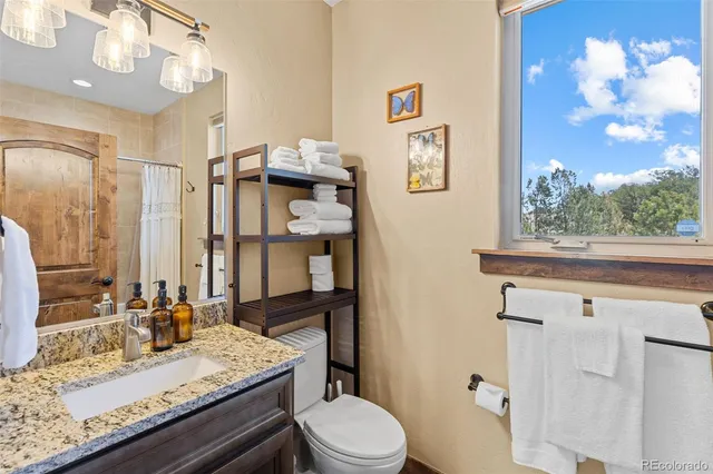 a bathroom with a granite countertop sink mirror vanity and toilet