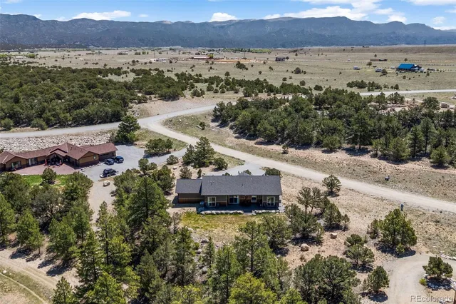 an aerial view of houses with a yard and mountain view in back