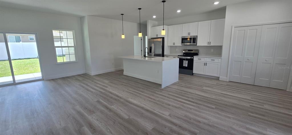 4464 Southwest 132nd Street Ocala, FL 34473 - Photo 4 of 17 a kitchen with stainless steel appliances kitchen island wooden floors wooden cabinets and entryway