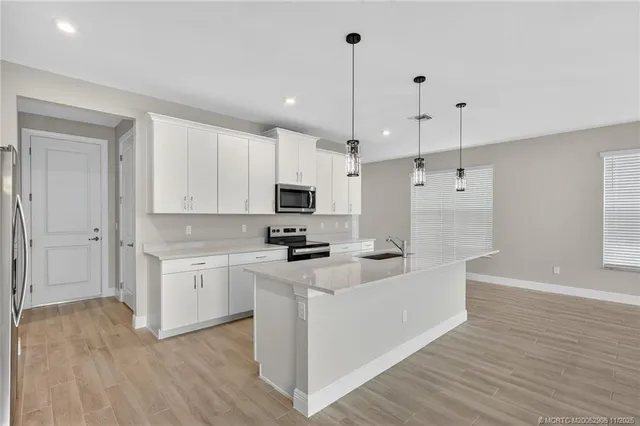 a kitchen with stainless steel appliances a sink a stove and a wooden floors