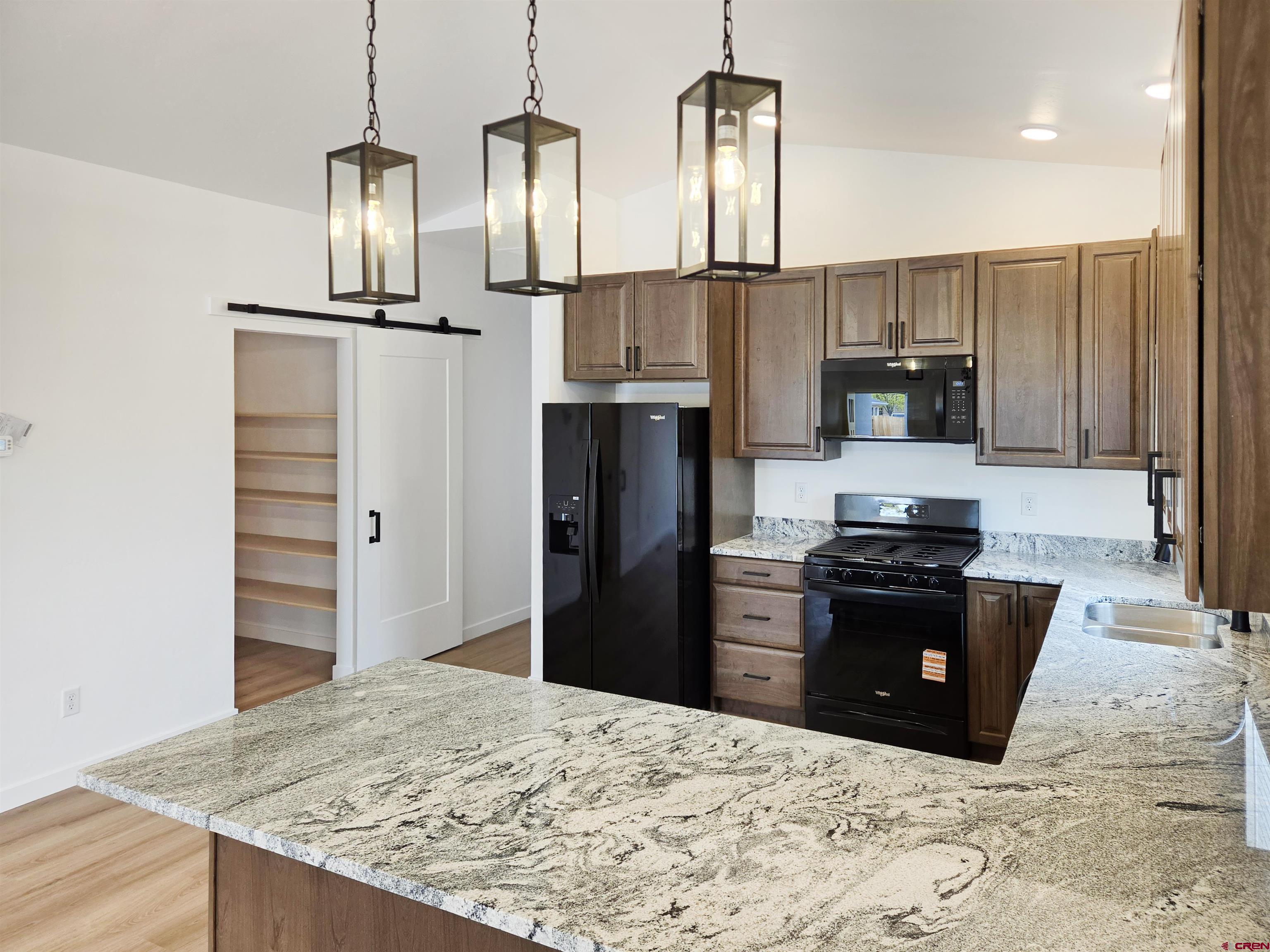 1456 Acoma Street Cortez, CO 81321 - Photo 7 of 26 a kitchen with granite countertop a refrigerator and a stove top oven