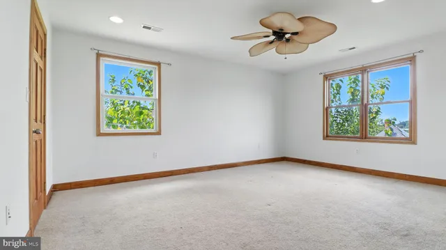 an empty room with windows and ceiling fan