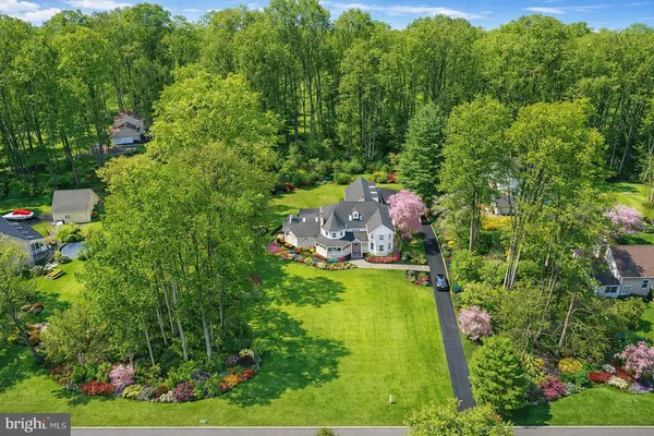 an aerial view of residential house with outdoor space and trees all around