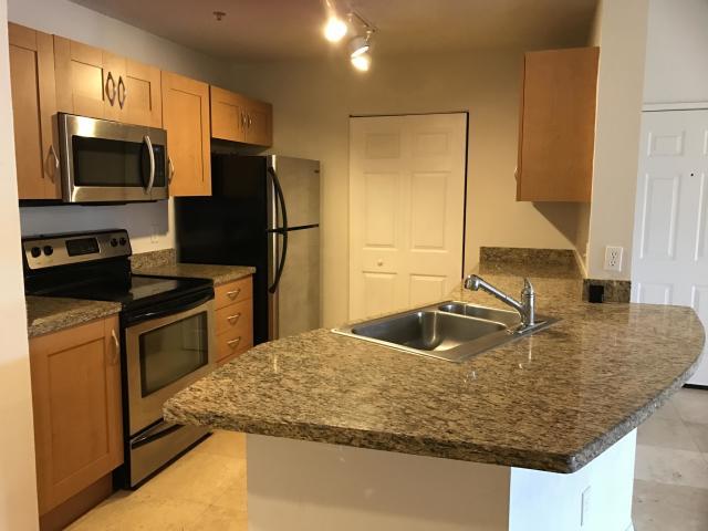 a kitchen with kitchen island granite countertop a sink and stainless steel appliances