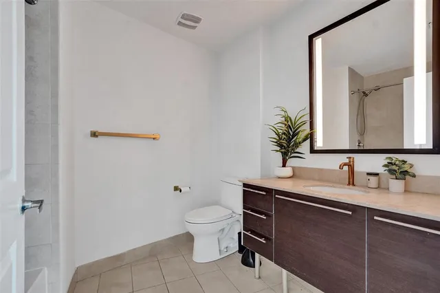 a bathroom with a granite countertop sink a toilet and a mirror