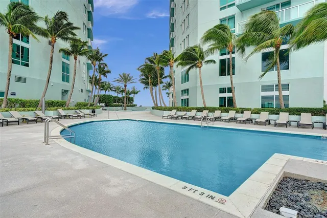 a view of swimming pool with outdoor seating and house in the background