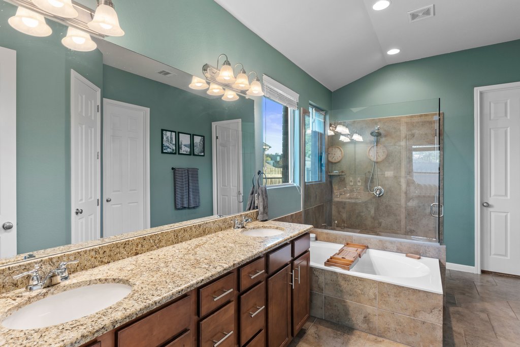 2902 Tempe Drive Cedar Park, TX 78641 - Photo 19 of 38 Bathroom with a bath, double vanity, a stall shower, vaulted ceiling, and suspended lighting