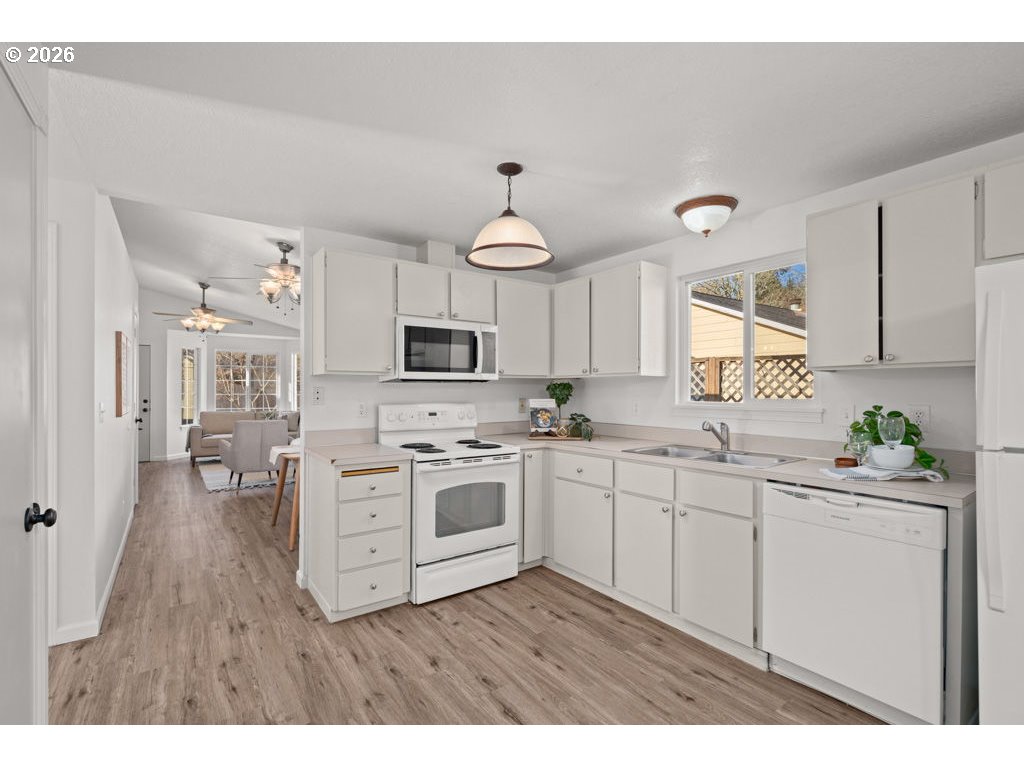 4482 Southwest 179th Avenue Beaverton, OR 97078 - Photo 13 of 37 a kitchen with white cabinets a sink dishwasher and a stove with wooden floor