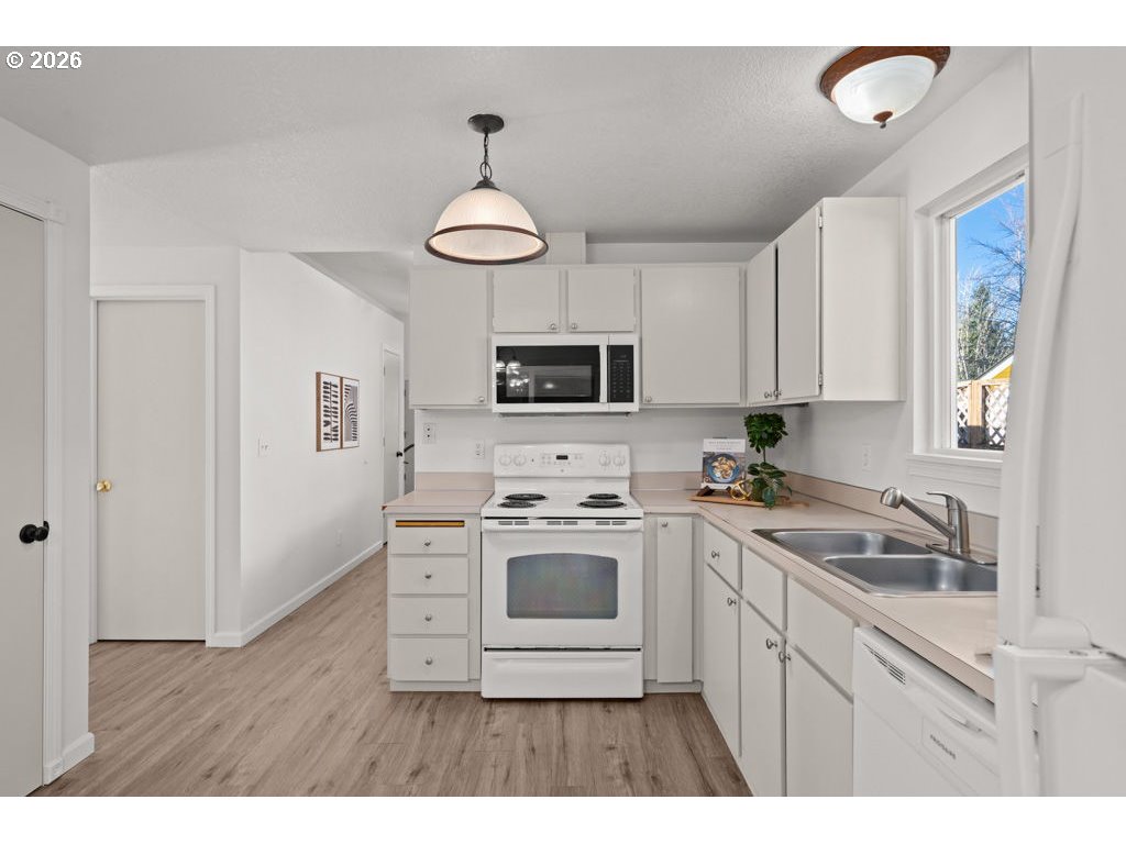 4482 Southwest 179th Avenue Beaverton, OR 97078 - Photo 14 of 37 a kitchen with a sink a stove a microwave and wooden floors