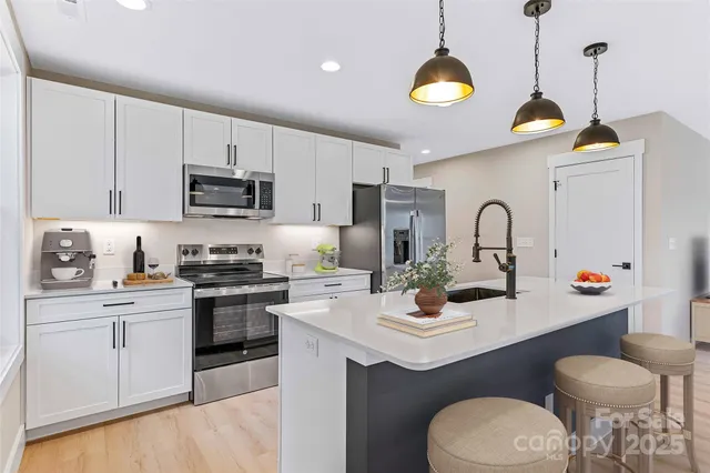 a kitchen with stainless steel appliances granite countertop a sink a stove cabinets counter space and a window