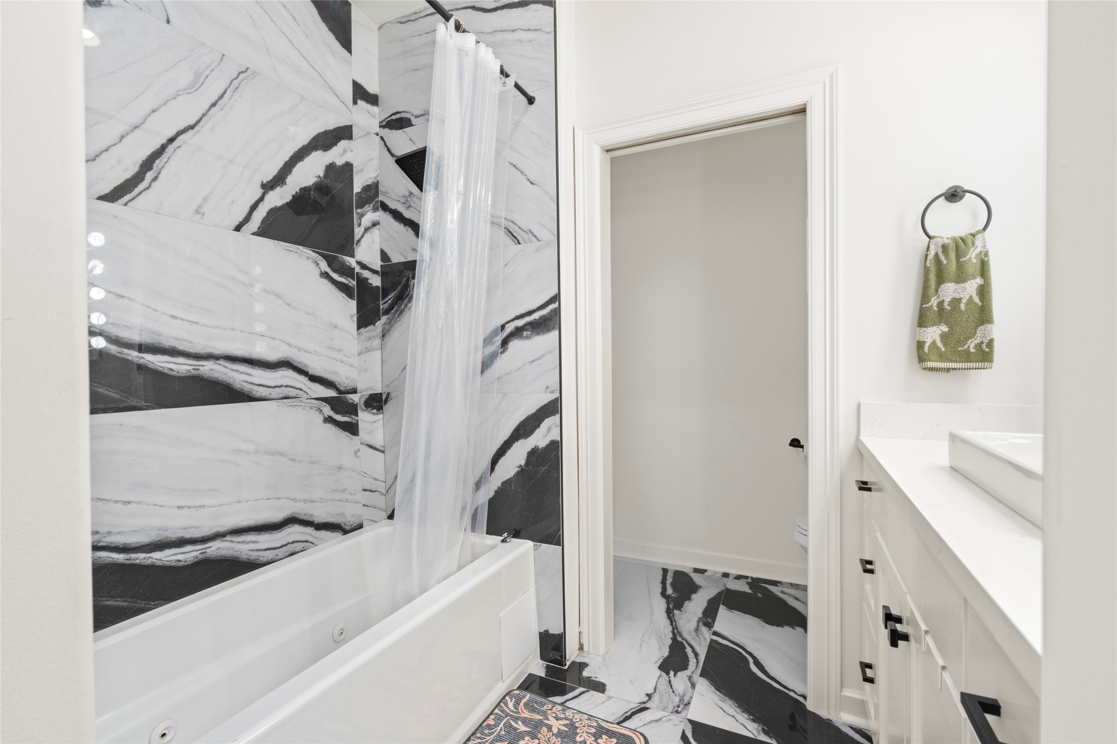914 Main Street, Unit 1008 Houston, TX 77002 - Photo 17 of 26 Spa like primary suite with a jetted contemporary tub and a cohesive black and white tile wall that ties into the flooring. Relax and unwind in the jetted tub after a long day.