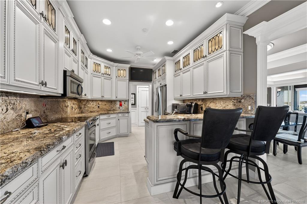 12500 Harbour Ridge Boulevard, Unit 48 Palm City, FL 34990 - Photo 7 of 28 a kitchen with stainless steel appliances granite countertop a table chairs sink and cabinets
