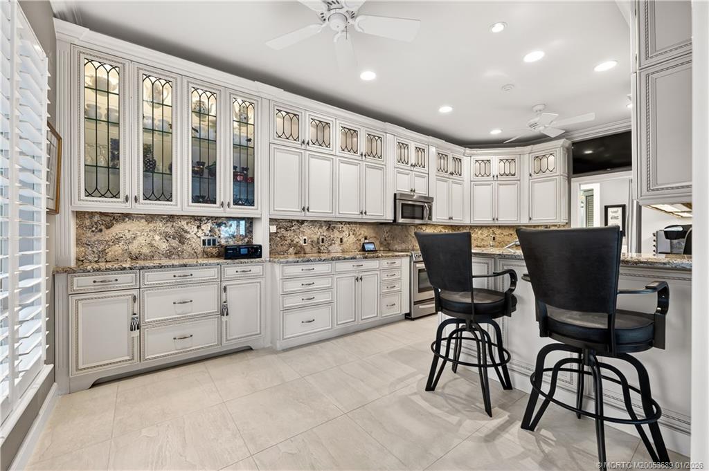 12500 Harbour Ridge Boulevard, Unit 48 Palm City, FL 34990 - Photo 9 of 28 a kitchen with stainless steel appliances kitchen island granite countertop a stove a table and chairs in it