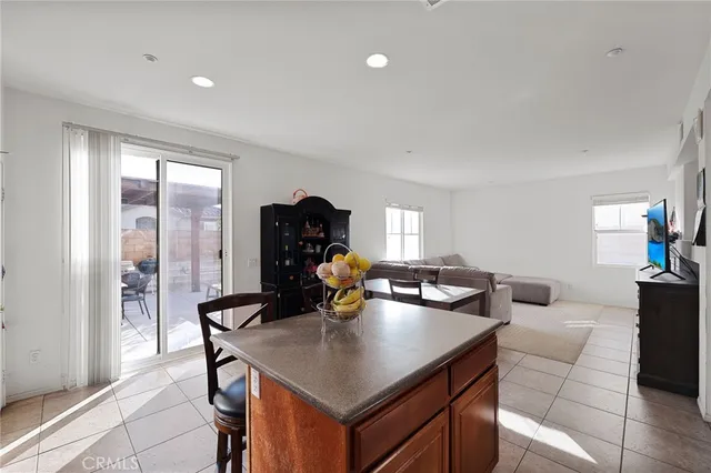 a dining area with stainless steel appliances kitchen island granite countertop a dining table chairs and a refrigerator