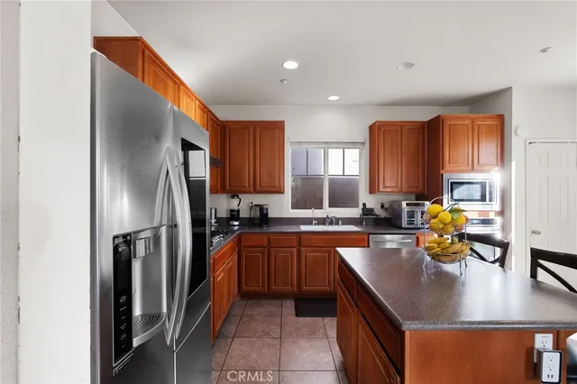 a kitchen with stainless steel appliances granite countertop a refrigerator a stove a sink a dining table and chairs