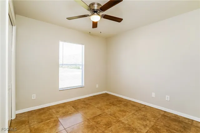 an empty room with a window and a fan