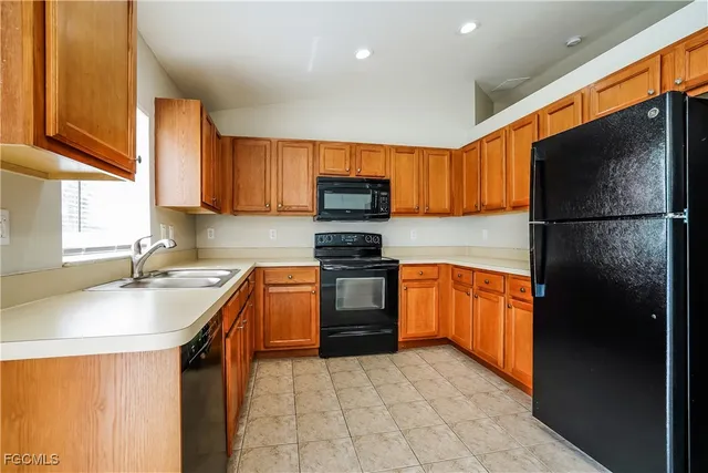a kitchen with granite countertop a refrigerator stove top oven a sink and dishwasher