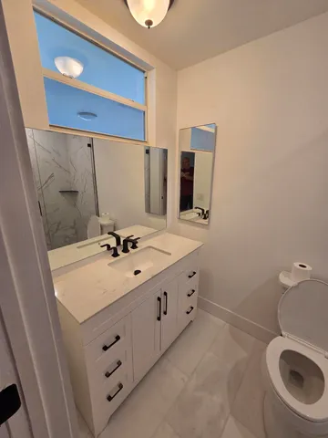 a bathroom with a granite countertop bathtub shower and toilet
