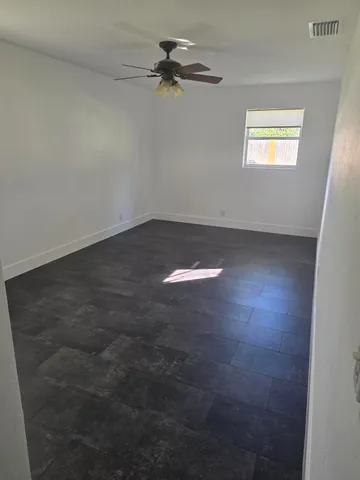 an empty room with a window and a fan