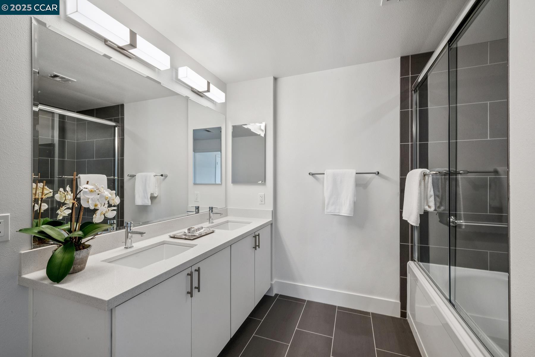 1000 Dewing Avenue, Unit 214 Lafayette, CA 94549 - Photo 14 of 23 a bathroom with a double vanity sink a large mirror a bathtub and shower