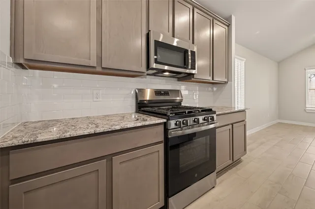 a kitchen with stainless steel appliances granite countertop white cabinets and a stove top oven