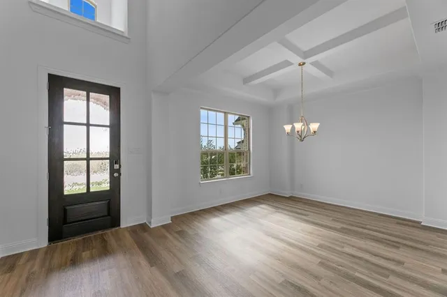 an empty room with wooden floor chandelier fan and windows