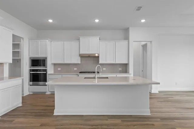 a kitchen with kitchen island sink stove and cabinets