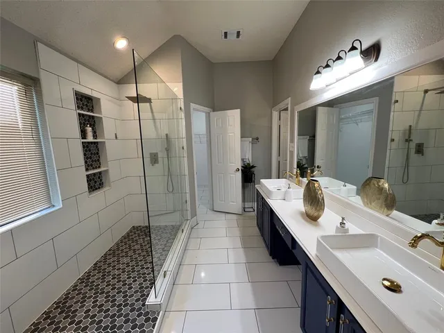 a bathroom with a double vanity sink a mirror and a shower
