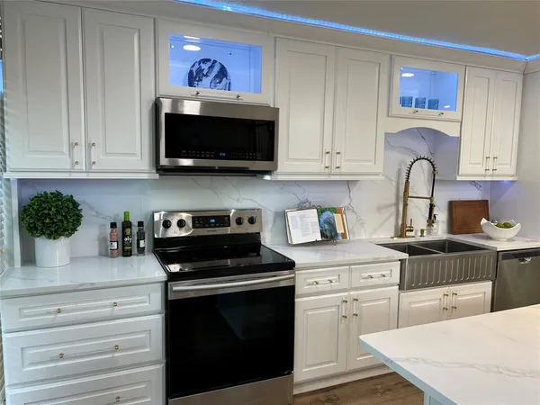 a kitchen with stainless steel appliances granite countertop a stove a sink and a microwave