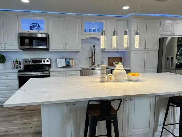 a kitchen with stainless steel appliances kitchen island a table chairs in it and wooden floors