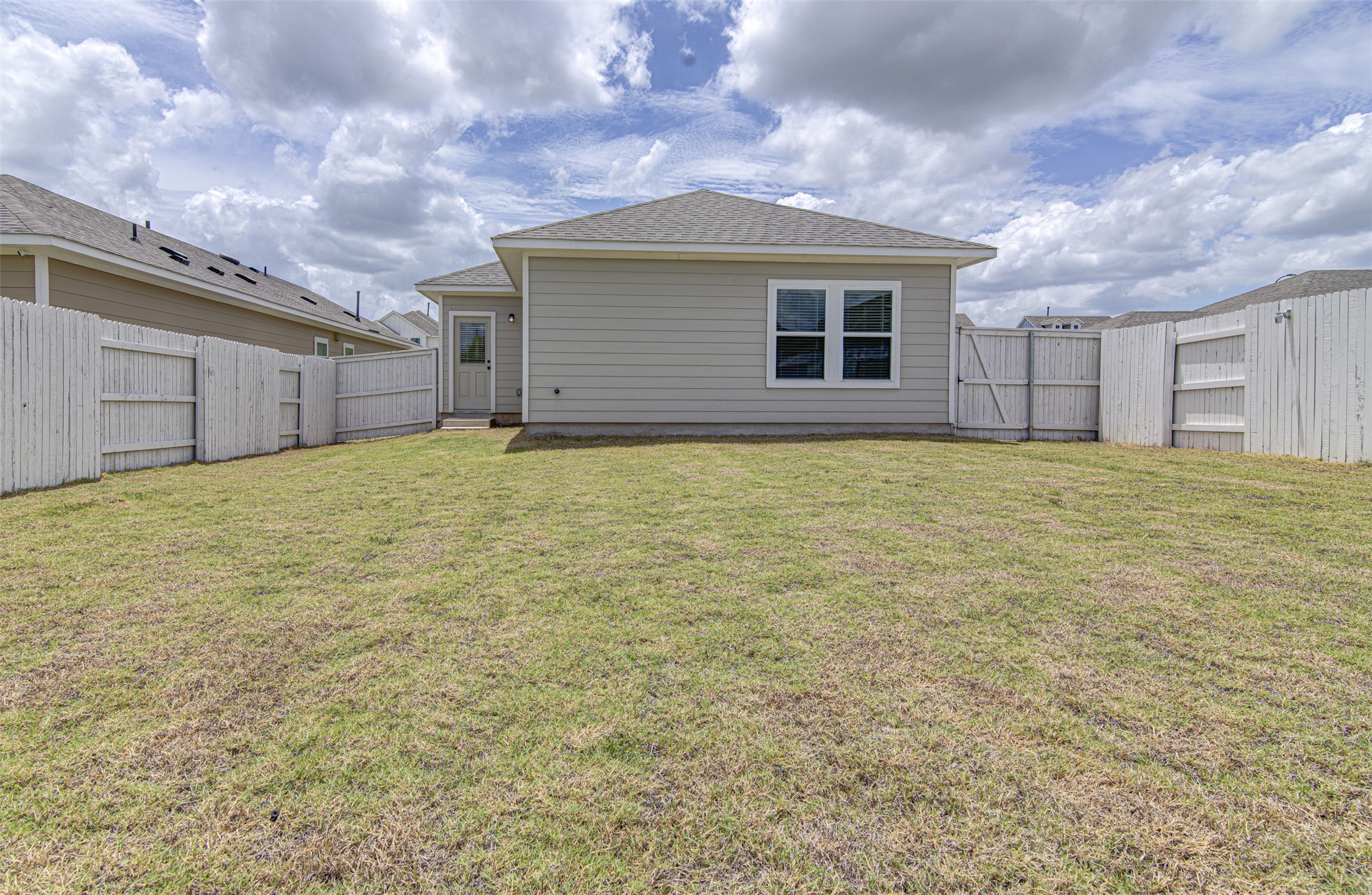 156 Tillage Road Elgin, TX 78621 - Photo 22 of 25 A generous backyard, fully enclosed with privacy fencing, offers ample space for outdoor living.