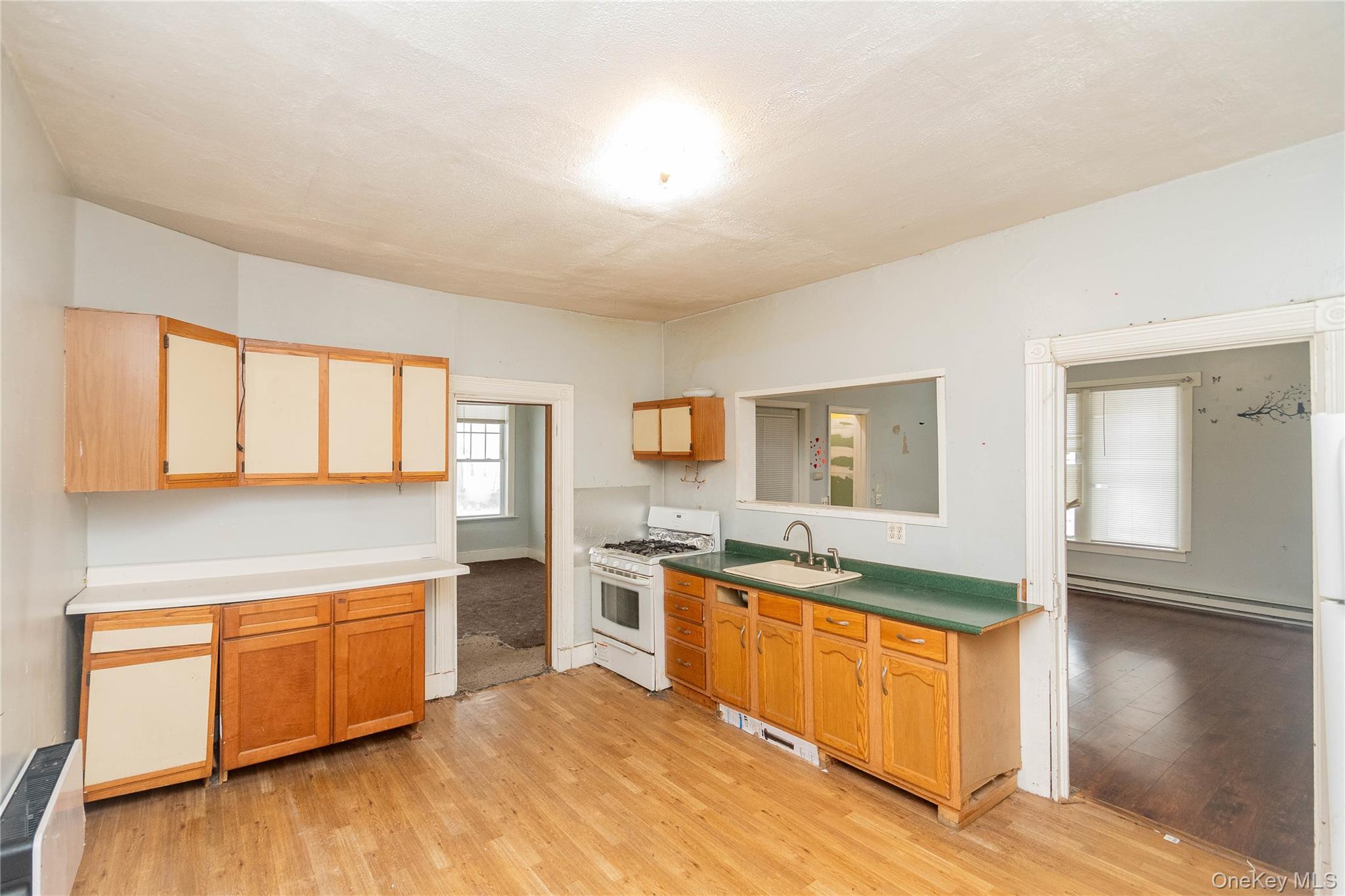 41 Edgar Street Liberty, NY 12754 - Photo 12 of 42 Kitchen with white appliances, a baseboard heating unit, light wood-style floors, and radiator