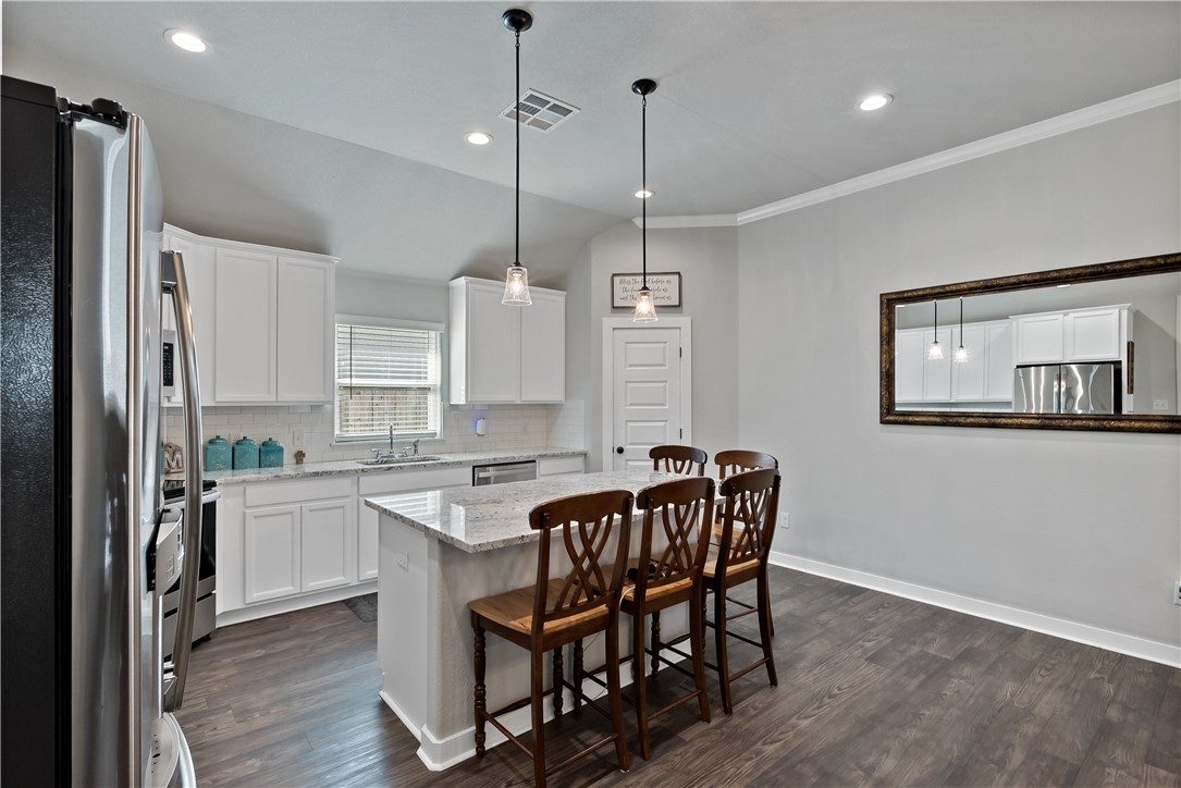 3161 Normandy Way Bryan, TX 77808 - Photo 11 of 27 a kitchen with stainless steel appliances granite countertop a stove a refrigerator a sink a dining table and chairs with wooden floor